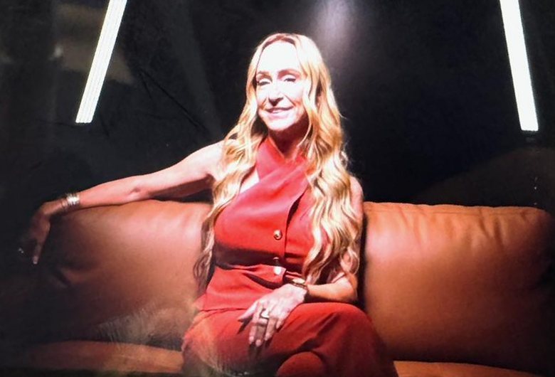 Stacey Melton seated on a leather sofa on set